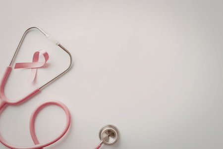 Pink stethoscope with a ribbon on a white background representing breast cancer awareness and healthcare support.の写真素材