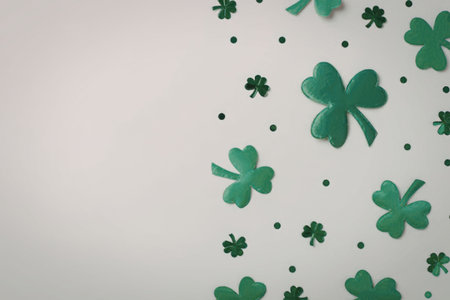 Green shamrocks and four leaf clovers scattered on a clean white background, symbolizing luck and...