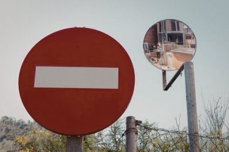 Red no entry sign and round mirror on roadside in winter, cold weather scene.