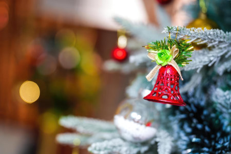 A Christmas tree decorated with red bell, ornaments, lights, and greenery