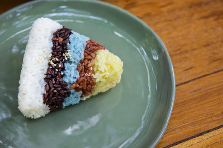 A vibrant sushi roll with various colors and ingredients on a gray plate, wooden table background