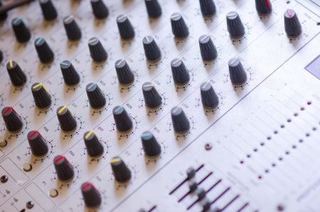 Close-up of an audio mixer with colorful knobs and sliders for sound adjustments