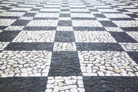 Close-up of a black and white checkered cobblestone street surface with textured stones.