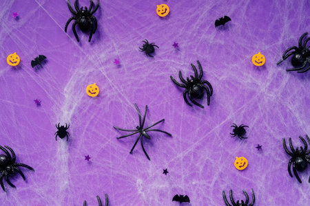 Spiders, bugs, and pumpkin emojis on purple surface for Halloween decoration