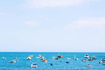 A natural scene of boats floating on a bright blue ocean under a clear sky.