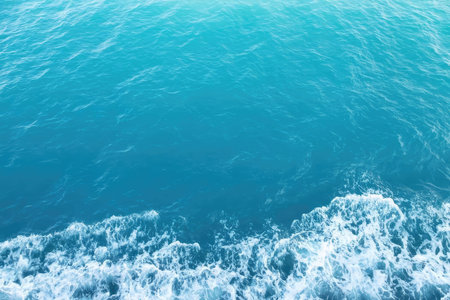 A natural scene of ocean waves crashing on the shore under a sunny sky with blue water