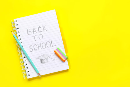 Notebook with text BACK TO SCHOOL and stationery on color background