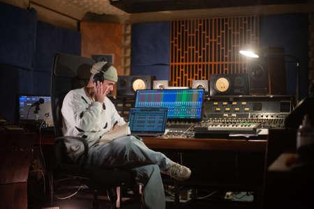 Concentrated young man listening to music sample in headphones. Sound engineer or music producer...