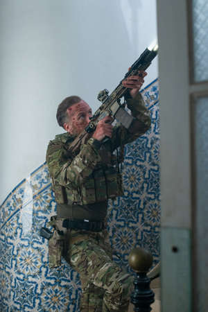 Focused army man during battle. Caucasian man with beard with smears of blood on face pointing...