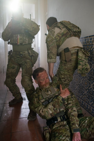 Tough military men helping wounded friend. Caucasian men with carrying injured teammate. Military, army, danger, fighting, airsoft conceptの写真素材