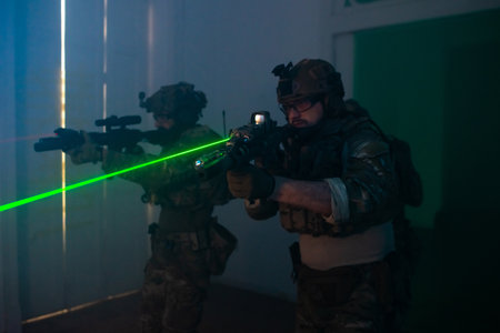 Absorbed men playing strikeball in dark room. Men in military uniforms aiming, looking for enemies. Army, military, game, hobby conceptの写真素材