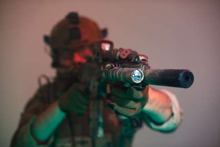 Blurry man aiming with machinegun. Armed man firing shotgun. Military man working out techniques of...