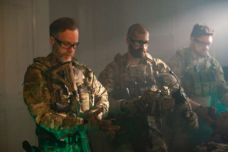 Bearded men in military equipment in dark room. Men in uniforms holding machine gun, getting ready for combat. Military, army, airsoft conceptの写真素材