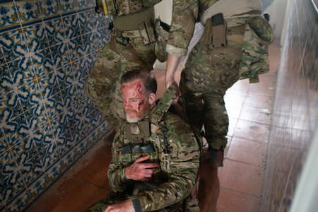 Strong military men helping wounded friend. Caucasian men with carrying injured teammate. Military, army, danger, fighting, airsoft conceptの写真素材