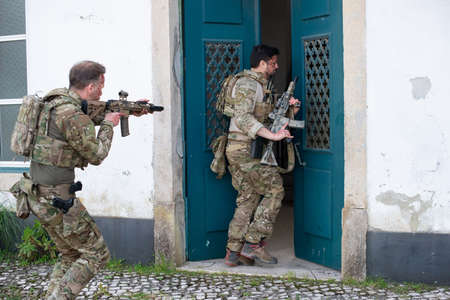 Brave soldiers getting ready to attack. Men with blood smears on faces entering house, aiming....