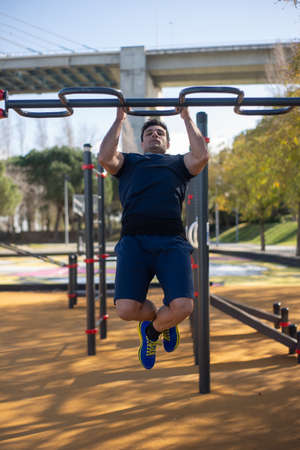 Attractive sportsman working out on sunny day. Man sportive clothes on open air sports ground,...