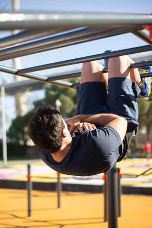 Back view of sportsman working out on sunny day. Man sportive clothes on open air sports ground,...