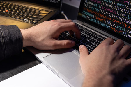 Close-up of man planning hacker attack. Man using laptop, typing code. Male hands on keyboard. Hacking, technology, cybercrime conceptの写真素材