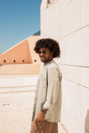 Contented Black man outdoors. African American man in casual clothes and sunglasses walking on sunny day. Portrait, city life conceptの写真素材