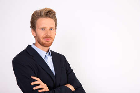 Portrait of successful young Caucasian businessman. Bearded man wearing blue shirt and black suit coat looking at camera and smiling. Success and confidence conceptの写真素材