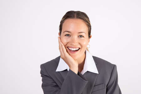 Portrait of cheerful young businesswoman smiling at camera. Caucasian woman wearing gray suit coat...