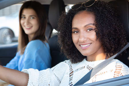 Female friends riding car. Two dark-haired women sitting in car, smiling. Friendship, transport conceptの写真素材
