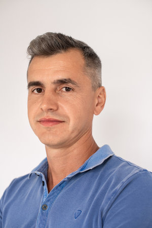 Portrait of serious mature man wearing blue T-shirt looking at camera. Caucasian man standing over...