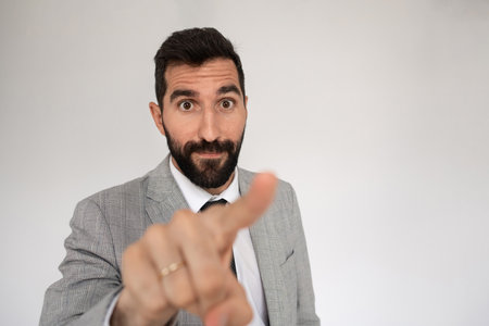 Caucasian man with beard pointing. Male model in suit looking at camera, gesturing. Portrait, studio shot, choice conceptの写真素材