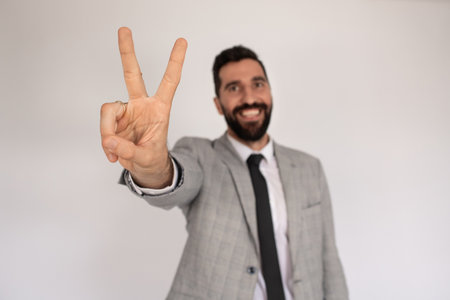 Portrait of outgoing man with beard. Male in suit gesturing, showing victory sign. Portrait, emotion conceptの写真素材