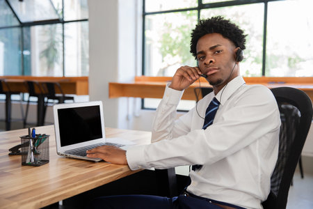 Focused male office worker with headset. Businessman looking at camera, holding microphone, meeting...