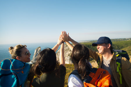 Happy hiking family putting hands together. Excited parents with teen daughters standing on mountain...