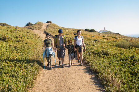 Happy father hiking with teen daughters and son. Family trekking in mountains in summer. Active...