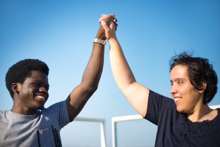 Portrait of biracial couple having walk on sunny day. African American man and Caucasian woman in wheelchairs on embankment, holding hands. Love, relationship, happiness conceptの写真素材