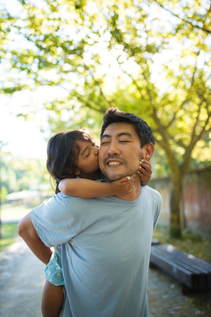 Close-up of Asian father and his daughter spending time in park. Happy young dad holding little kid...