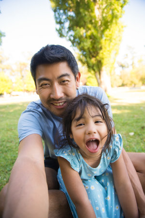 Asian dad taking selfie with his beautiful daughter. Handsome man spending vacation with his little...