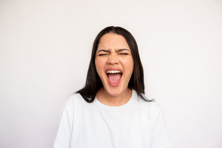 Portrait of frustrated young woman shouting on white background. Caucasian lady wearing white...