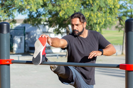 Portrait of serious man training legs on horizontal bar. Caucasian man standing with his prosthetic...