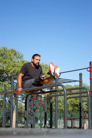 Portrait of active man with prosthetic leg on bars. Young man standing on his both hands on bars...