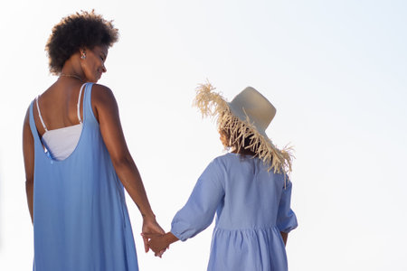 Back view of tender mother and daughter holding hands on beach. African American family spending time together on open air. Leisure, family time, togetherness conceptの写真素材