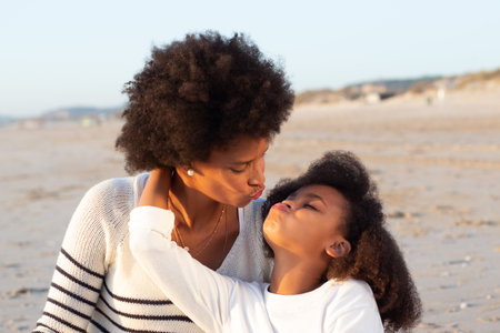Portrait of happy family on beach. Mother and daughter making faces, hugging, kissing. Family, love, bonding conceptの写真素材