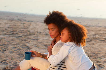 Portrait of relaxed family at sunset. Mother and daughter smiling, hugging, looking down. Family,...