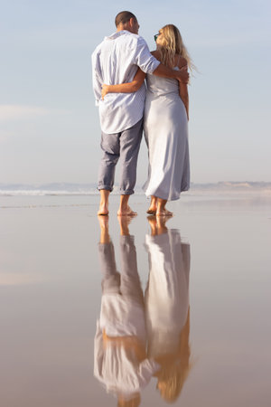 Back view of family walking on beach. Caucasian man with shaved head and woman in casual dress hugging. Love, family, travelling conceptの写真素材