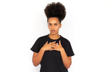 Portrait of frowning young woman looking at camera against white background. African American woman...