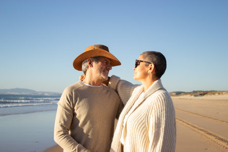 Lovely senior couple standing at seashore, hugging and looking at each other. Man in cowboy hat and short-haired woman in sunglasses enjoying vacation at seaside together. Leisure, retirement conceptの写真素材