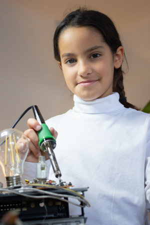 Portrait of content girl with solder in school lab. Schoolgirl having classes in electronics....