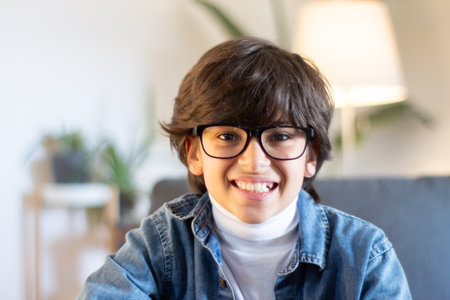 Portrait of boy geek in glasses and blue jeans jacket smiling at camera. Education, childhood...
