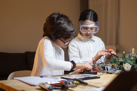 Focused children doing experiment in physics together in school lab. Girl and boy taking...