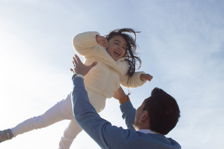 Loving Japanese father and daughter on sunny day. Japanese family walking, laughing, fooling around,...