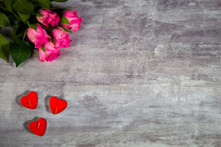Closeup footage of pink roses and red candles in shape of heart lying on grey wooden surface filmed from above. Creative decoration for celebrating Valentines Day or romantic date. Theme of engagementの写真素材