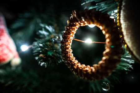Christmas festive decorations hanging on pine tree filmed in closeup. New Year fir is illuminated by shiny garland and glittering toys. Atmosphere of traditional winter holidays. Xmas design on spruceの写真素材